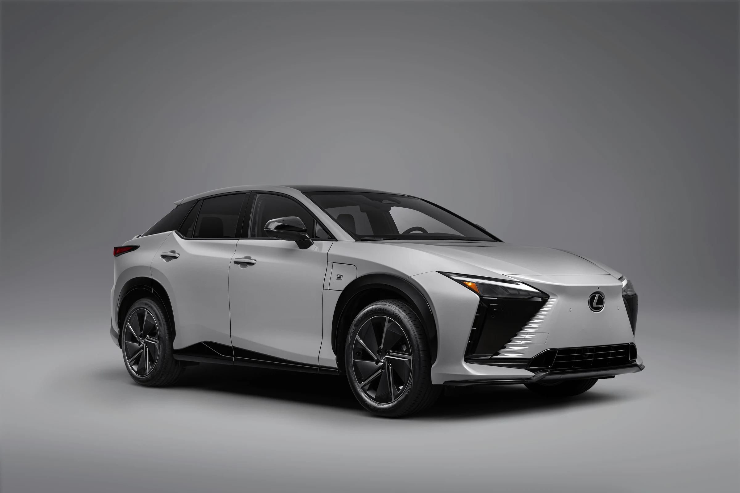 Lexus RZ 2027 550e F SPORT AWD en gris, de tres cuartos frontales, sobre un fondo de estudio