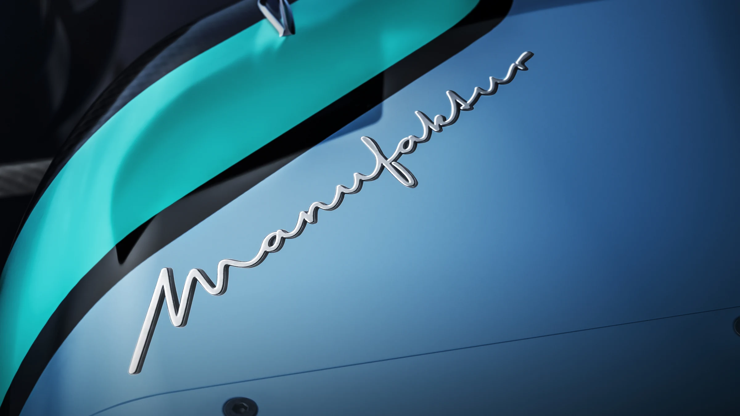 Logo manuscrito de MANUFAKTUR en blanco sobre un panel azul con borde turquesa del Mercedes W17