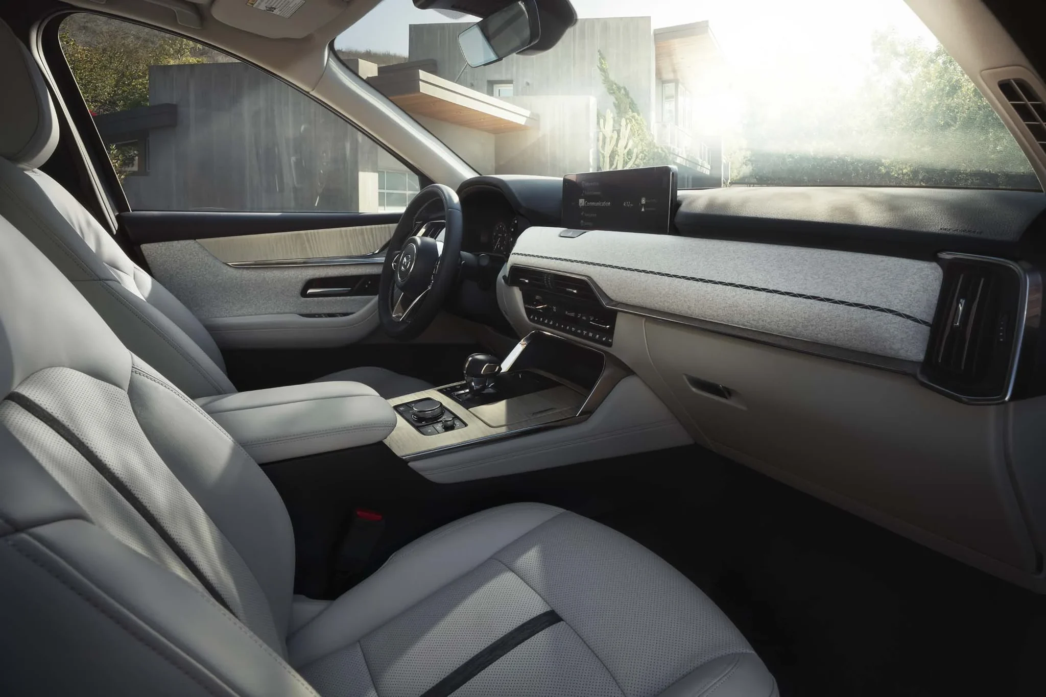 Cabina del Mazda CX-90 con asientos de cuero claro y luz entrando por las ventanillas