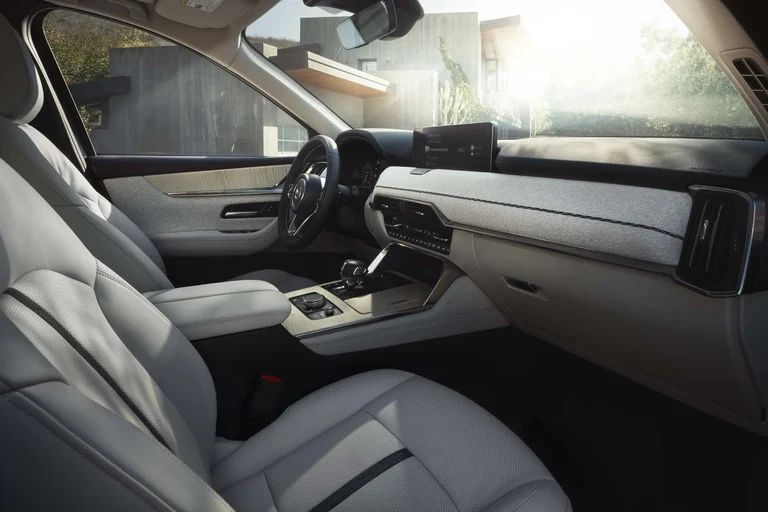 Cabina del Mazda CX-90 con asientos de cuero claro y luz entrando por las ventanillas