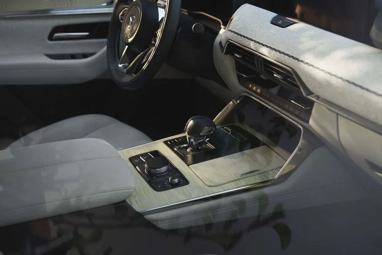 Palanca de cambios y selector de la consola central del Mazda CX-90, con acabado de madera clara