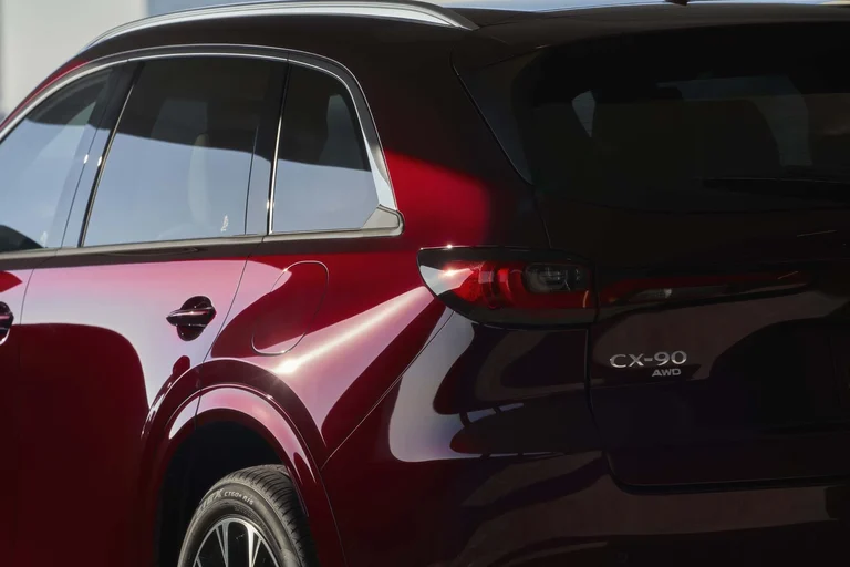 Costado trasero de un Mazda CX-90 rojo, con la ventanilla trasera y la insignia CX-90 AWD en la compuerta