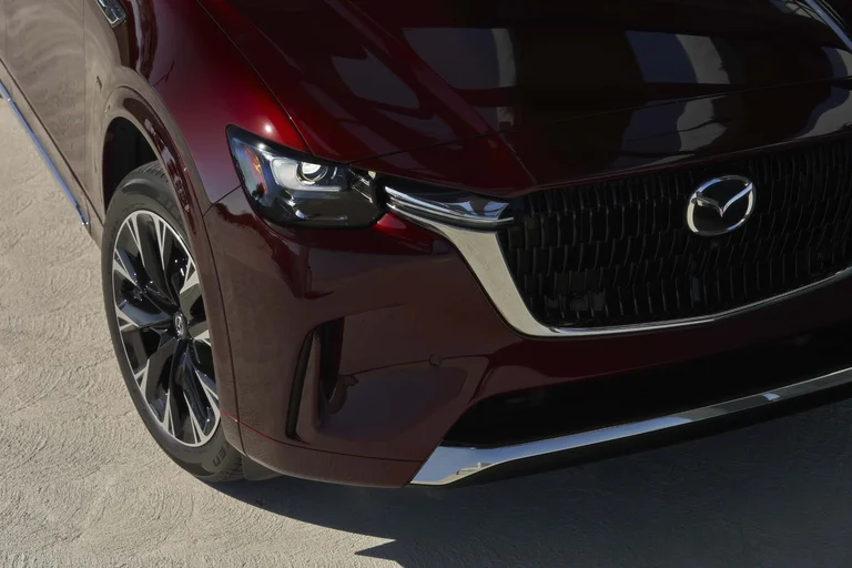 Frente de un Mazda CX-90 rojo con el faro, la parrilla y el rin delantero
