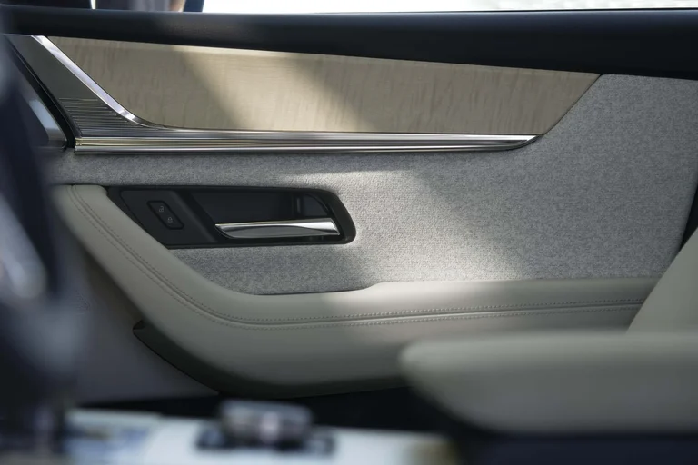 Panel de la puerta del Mazda CX-90 con tela gris, cuero claro y manija cromada