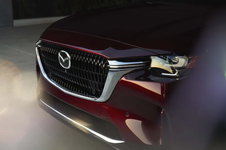 Parrilla y faro delantero de un Mazda CX-90 rojo, en primer plano