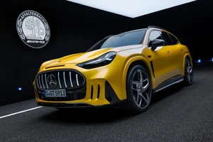 Mercedes-AMG GT SUV amarillo visto de frente y de costado en un estudio oscuro, con la parrilla vertical y el emblema de AMG