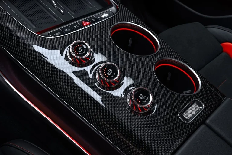 Consola central del Mercedes-AMG GT SUV con tres mandos rotativos rojos del AMG RACE ENGINEER sobre fibra de carbono