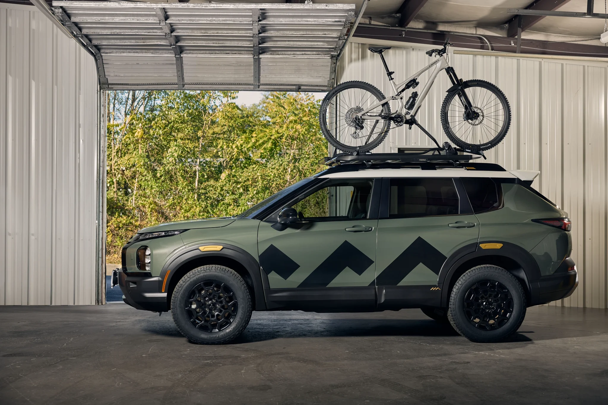 Perfil del Outlander Diamond Trail Edition modificado, con una bicicleta en el techo, dentro de un taller