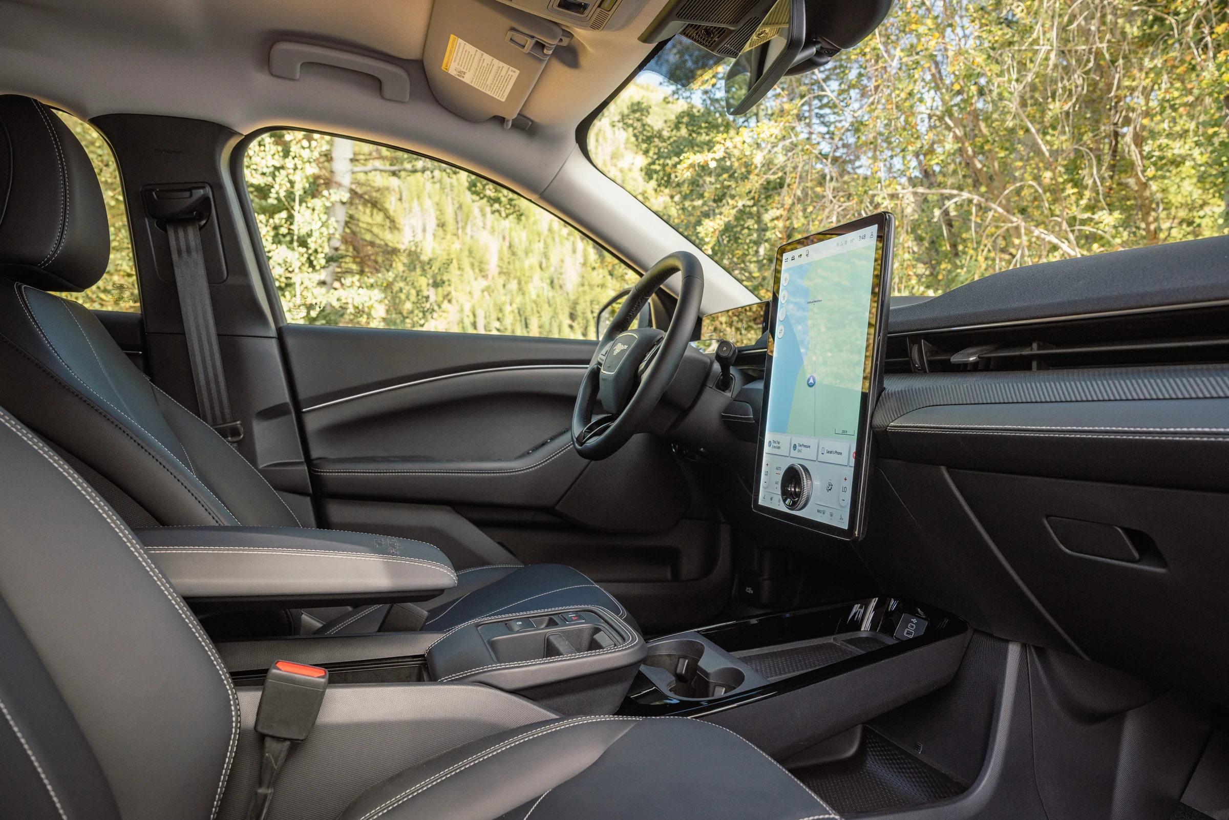 Interior del Mustang Mach-E Trail con la pantalla vertical central, el volante y los asientos delanteros
