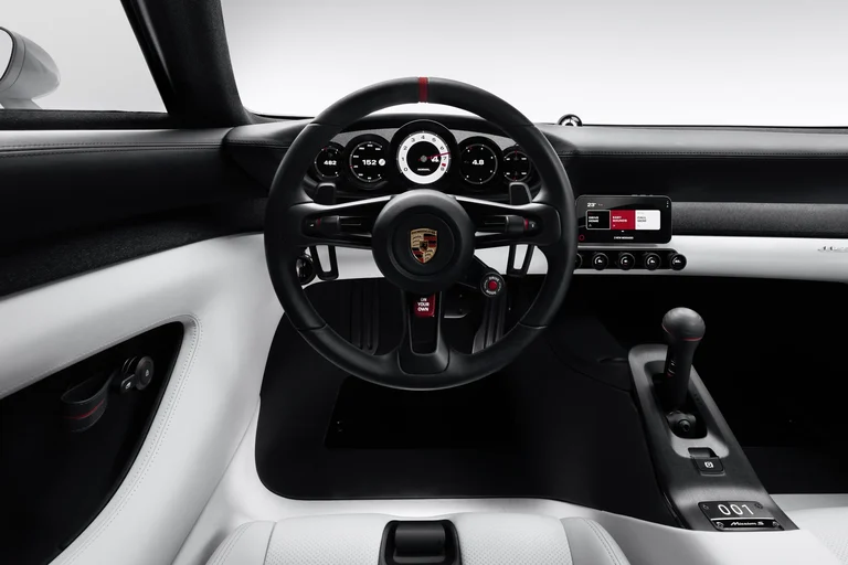 Interior del Porsche Mission S con volante, cinco instrumentos redondos, palanca de cambios y asientos blancos
