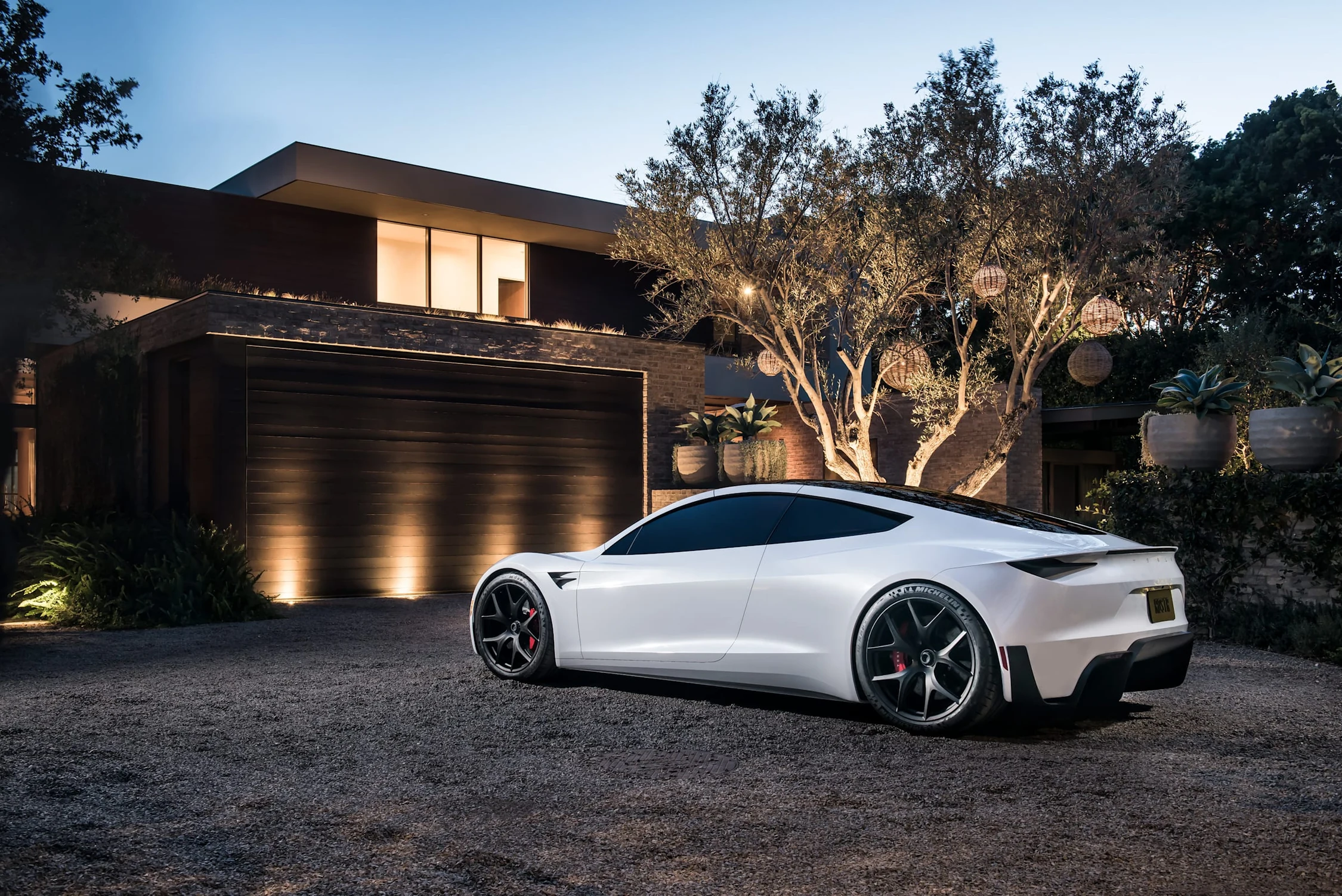 Tesla Roadster blanco, prototipo de 2017, estacionado frente a una casa moderna al anochecer