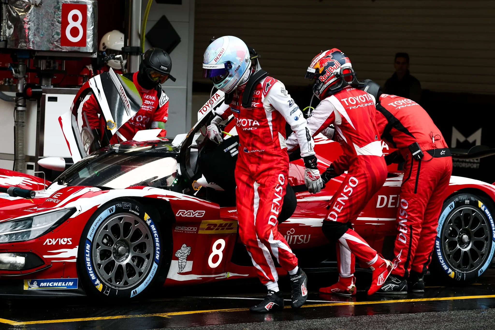 Mecánicos de Toyota Racing y dos pilotos con monos rojos durante una parada del Toyota número 8 en Barcelona