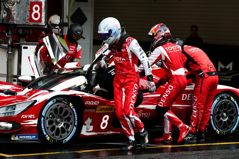 Mecánicos de Toyota Racing y dos pilotos con monos rojos durante una parada del Toyota número 8 en Barcelona