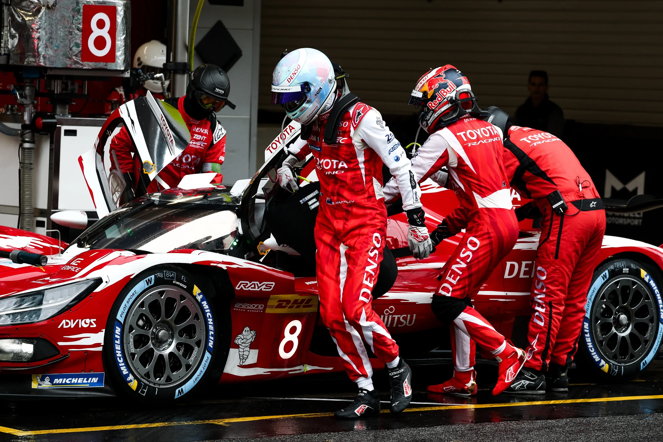 Mecánicos de Toyota Racing y dos pilotos con monos rojos durante una parada del Toyota número 8 en Barcelona