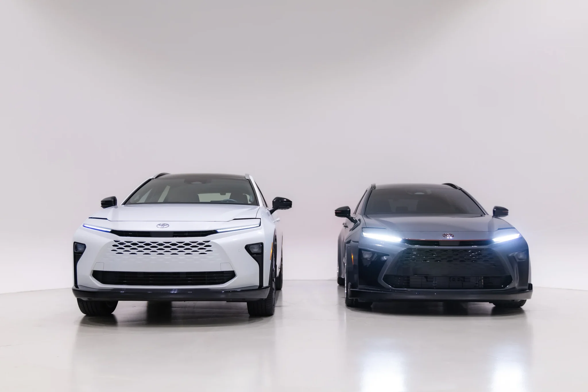 Toyota Crown Signia GT-S Concept con la luz diurna encendida, junto a un Crown Signia blanco, vistos de frente