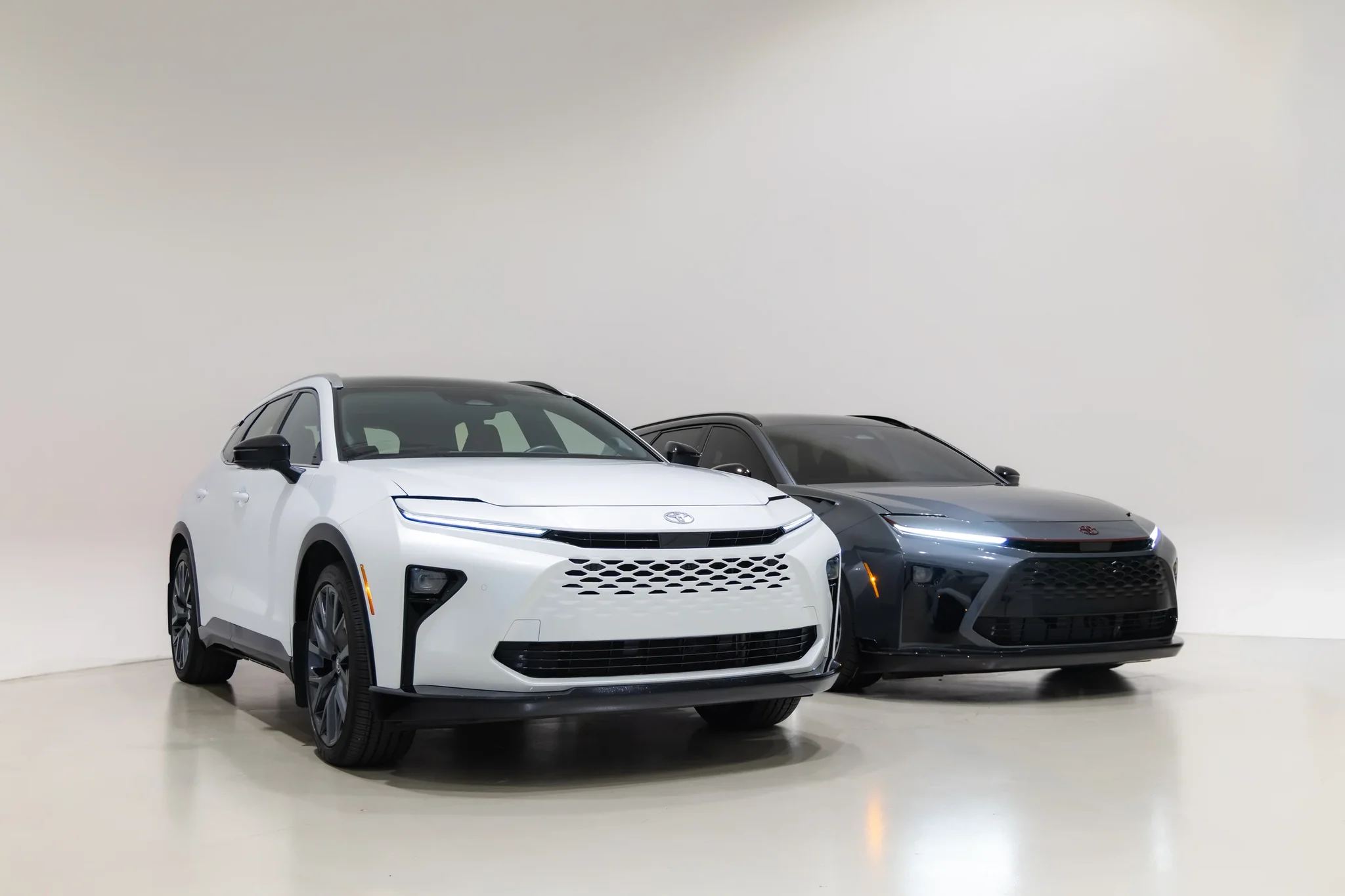 Frente de un Crown Signia blanco junto al Toyota Crown Signia GT-S Concept gris oscuro, de tres cuartos