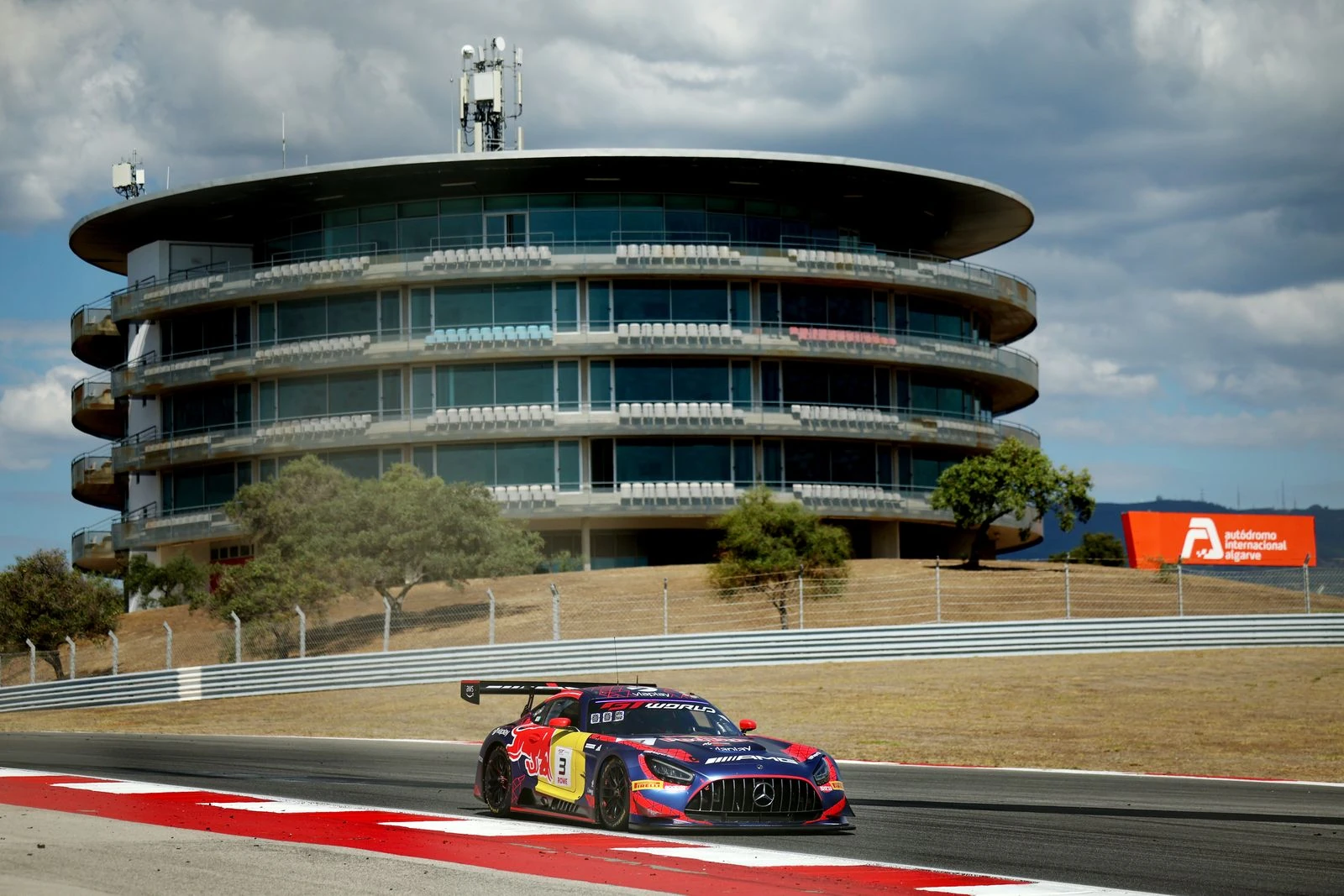 Mercedes-AMG GT3 número 3 de Verstappen Racing en pista, con el edificio de control del autódromo de Portimão al fondo