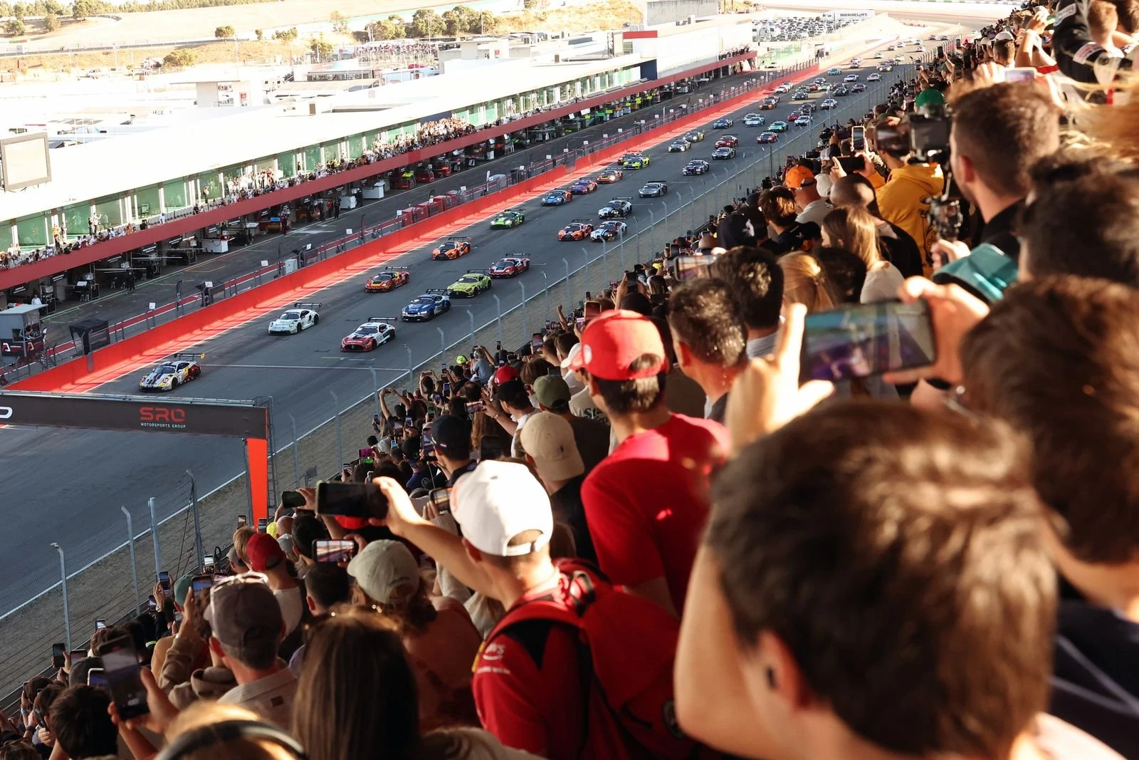 Los autos del GT World Challenge Europe recorren la recta principal de Portimão ante la tribuna llena de aficionados