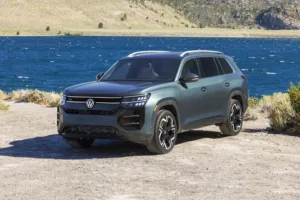 Volkswagen Atlas 2027 Sacramento Green de frente, junto a un lago